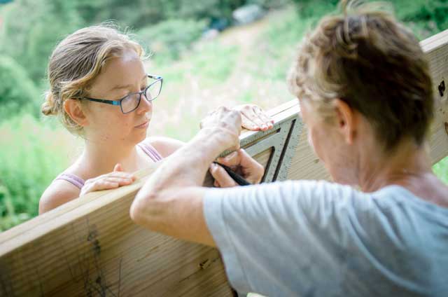 women's carpentry class students using a speed square for marking a straight line on a board