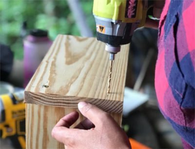 woman using a power drill to do carpentry and build a bench