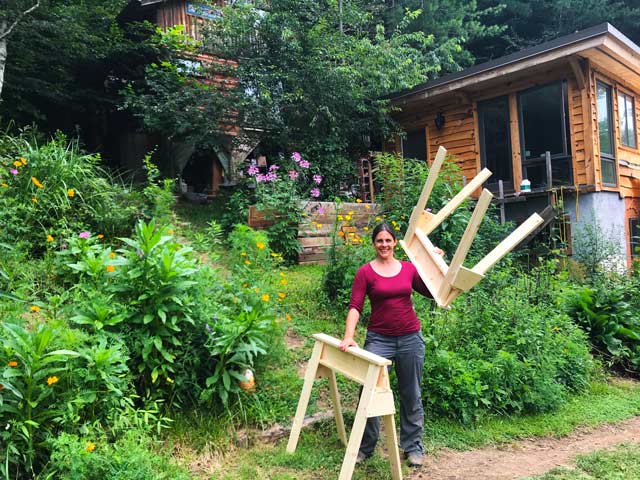 carpentry student holding two sawhorses she built during a woodworking class
