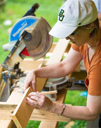 woman with safety glasses using a carpenter's pencil to mark on wood