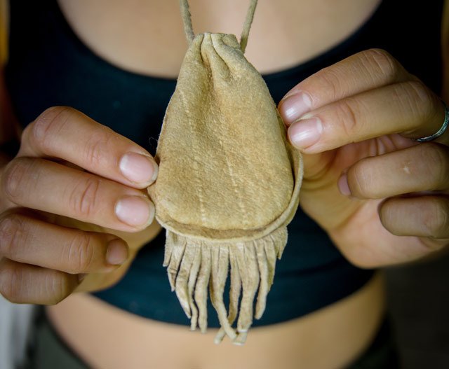 closeup of handmade buckskin medicine pouch with hands