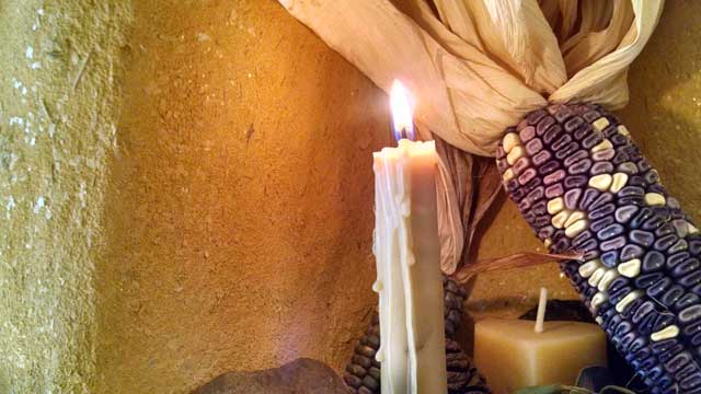 beeswax candle with corn on an altar