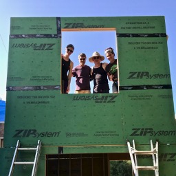 group of people putting up a wall for a tiny house