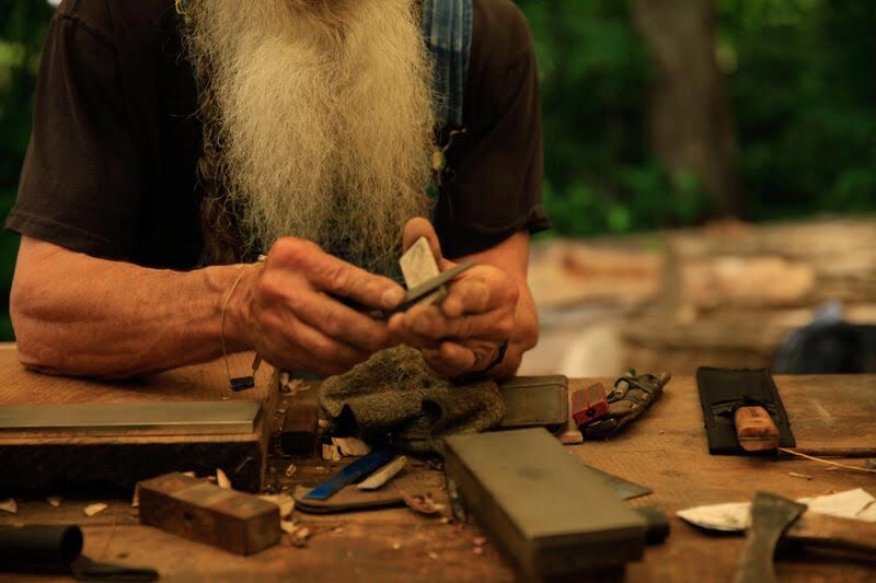 sharpening a knife with a table of sharpening stones laid out