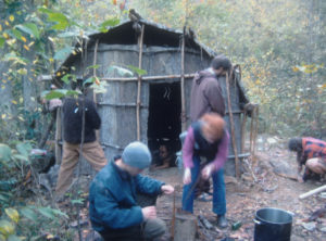 practicing primitive skills in front of bark hut