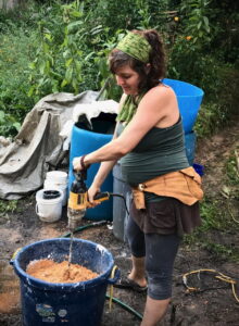 woman using paint mixer attachment and drill to mix DIY paint in a bucket