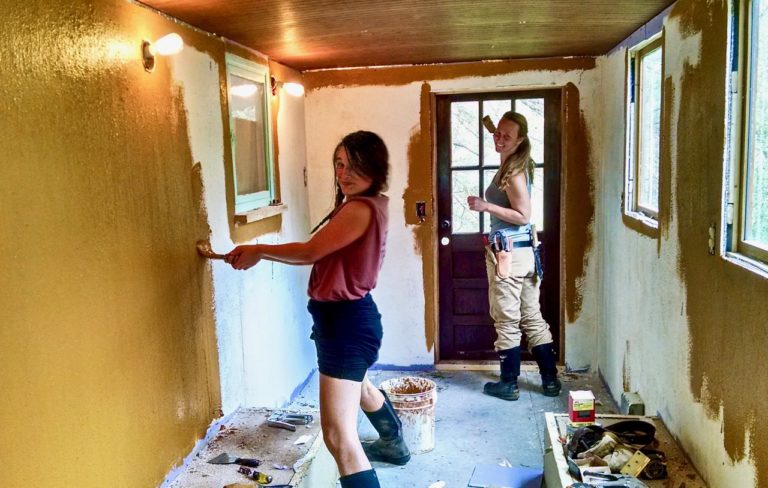 apprentices applying earthen paint to walls