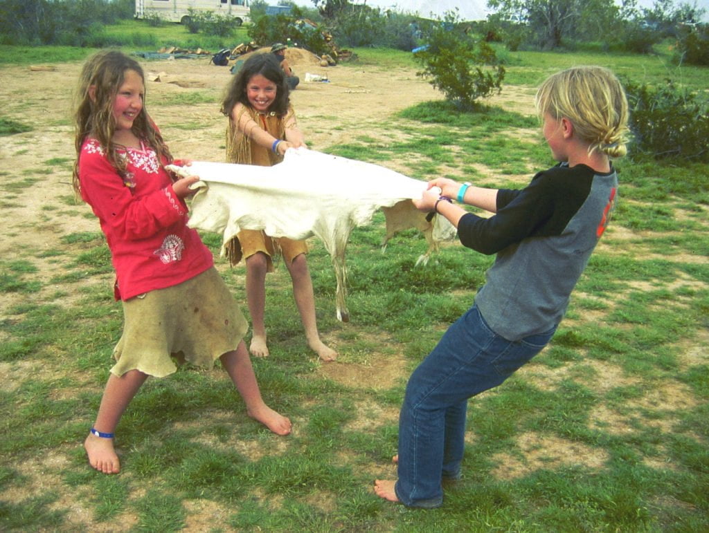 kids stretching a deer hide to soften it for hide tanning