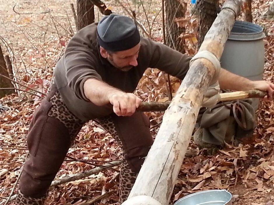 man wringing out a hide during brain tanning