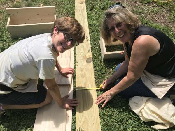 two women measuring a board in a home building workshop