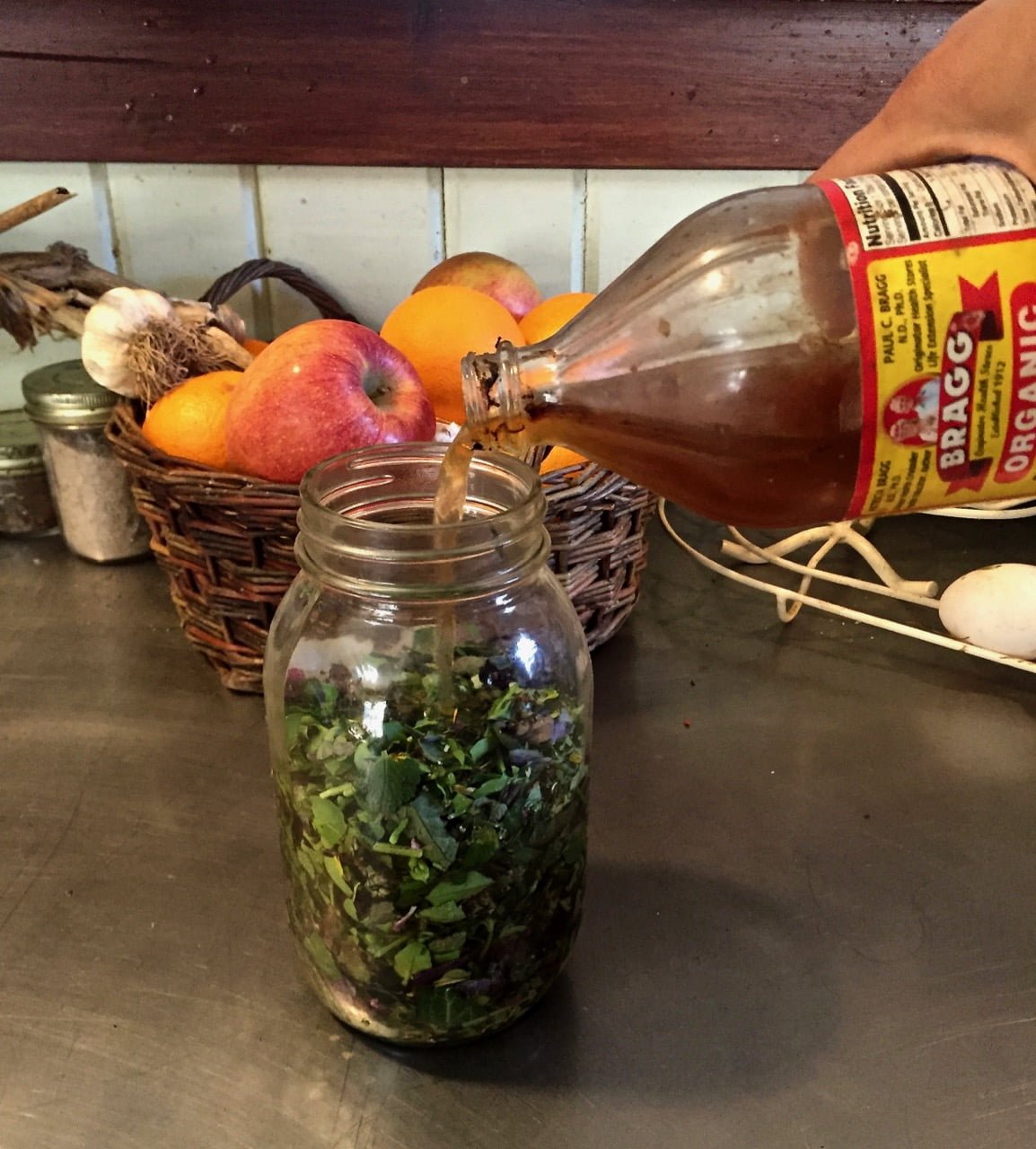 pouring vinegar over herbs in a bottle