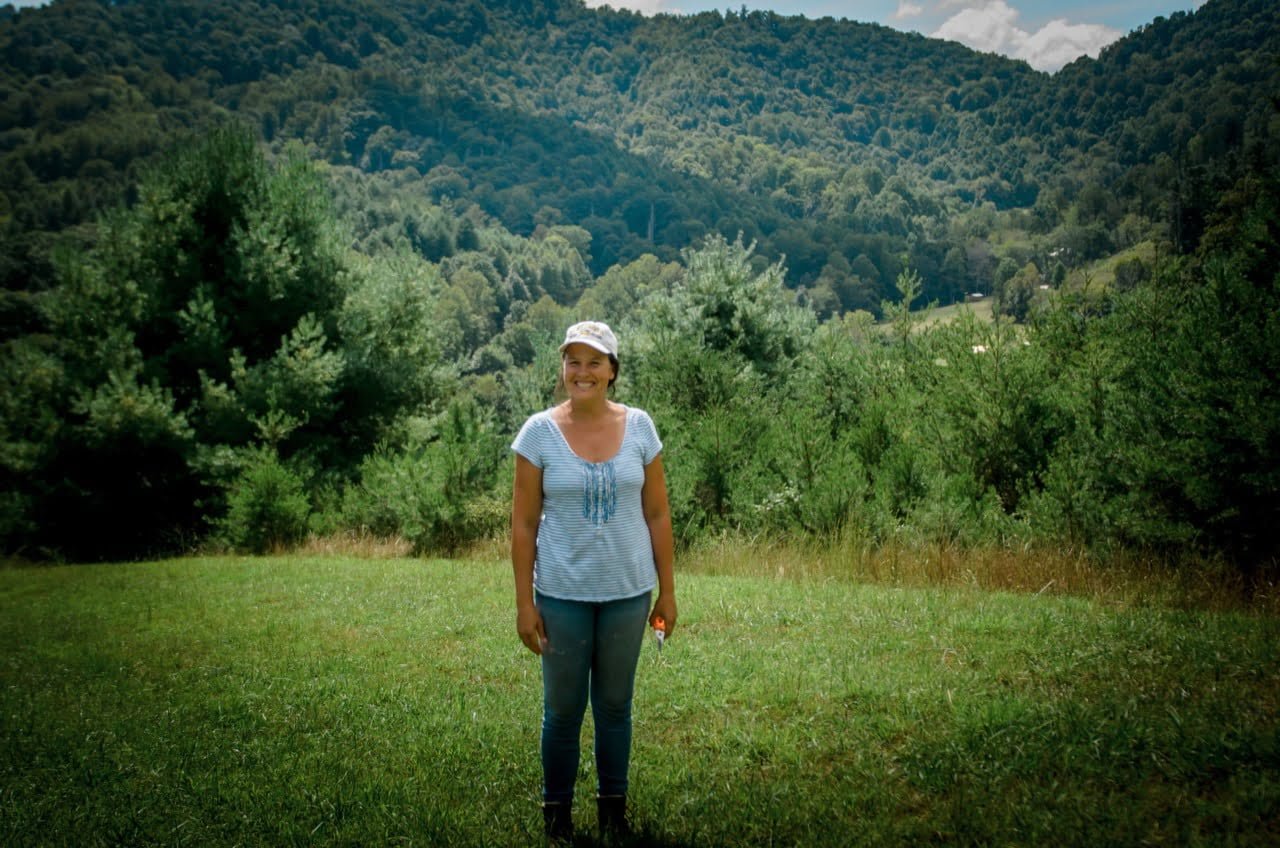 woman standing a field with mountains living off the land