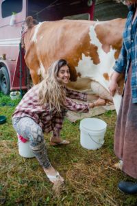 woman milking a cow helping a neighbor