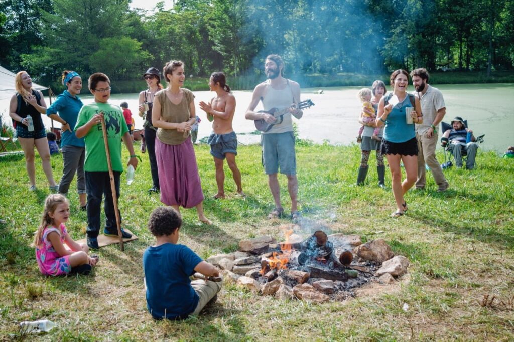 group of people singing around a fire including children