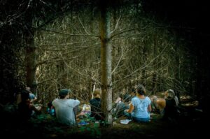 group of people in wilderness sitting at the base of a tree