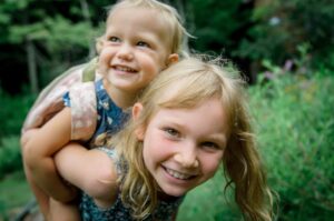 toddler riding on older child's back smiling