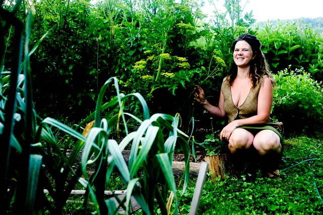 Natalie next to a garden bed with garlic 