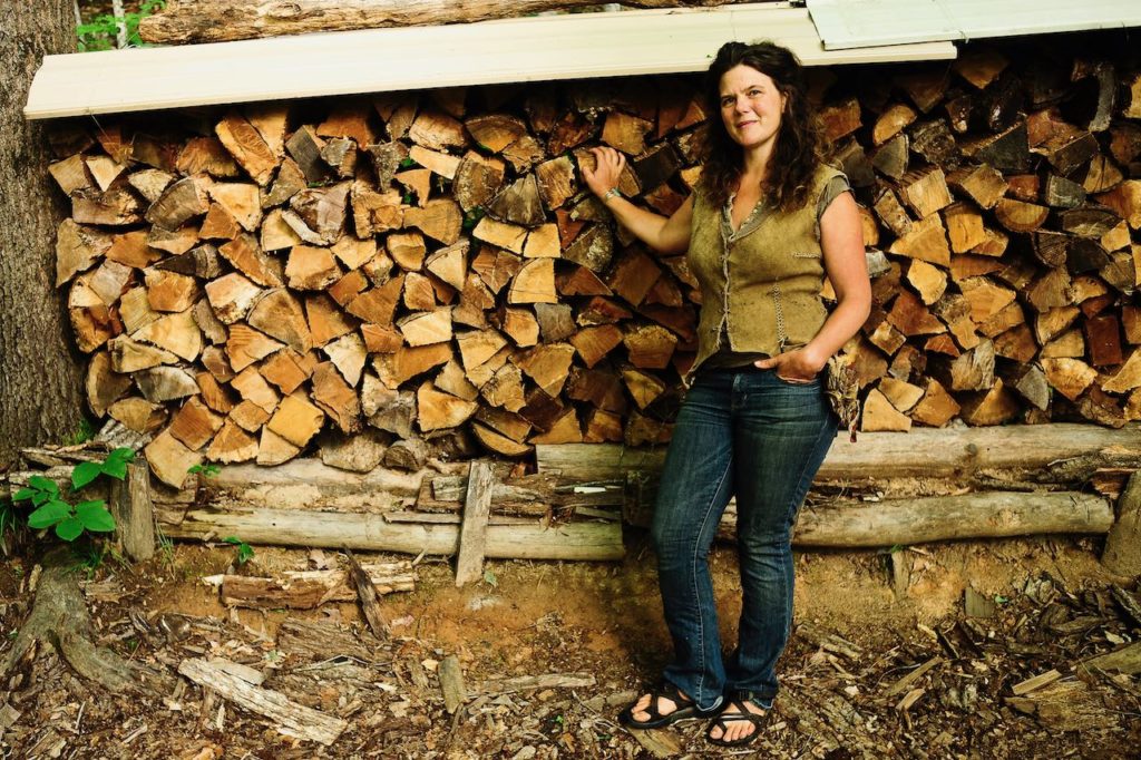Natalie Bogwalker in front of firewood stack