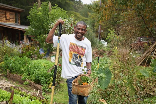 Man in garden with rake and basket of vegetables