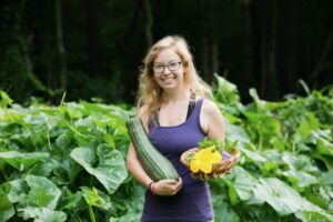 woman in garden with overgrown zucchini