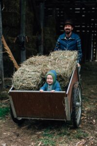 man with wagon load of hay and child in the wagon