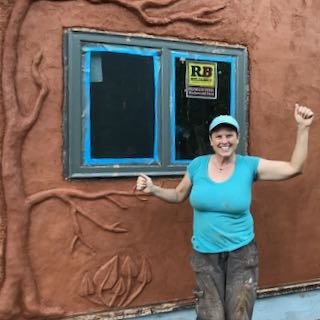 woman in front of tiny house with natural plaster