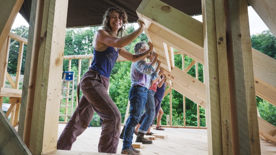 group of women raising a wall in a tiny house