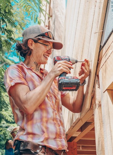 tiny house class student using impact driver to put up siding