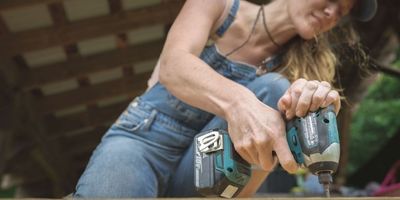 woman using impact driver to build tiny house