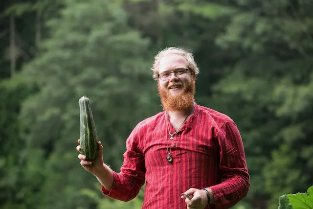 man holding up one zucchini