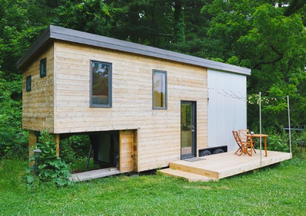 stylish tiny house with front deck and lush green lawn