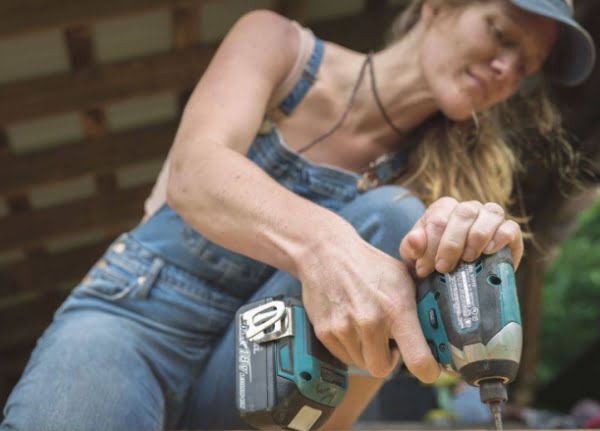 woman using impact driver to build a tiny house