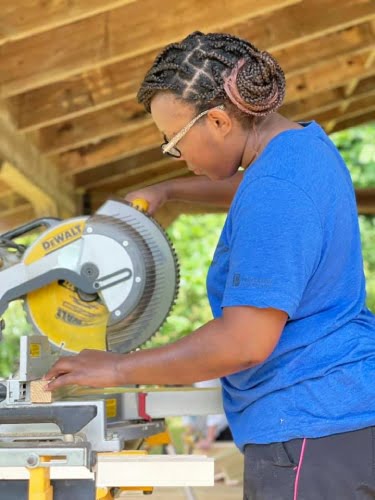 woman using chop saw to cut lumber for tiny house