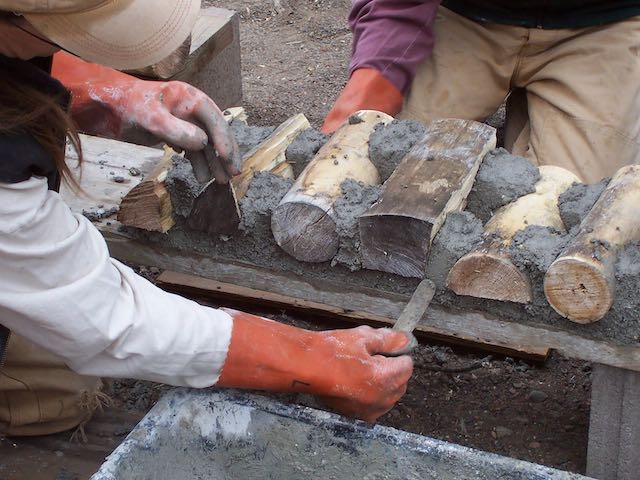 details of hands working on cordwood construction