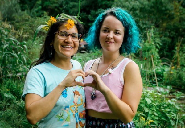 two young women smiling and making a heart with their hands together