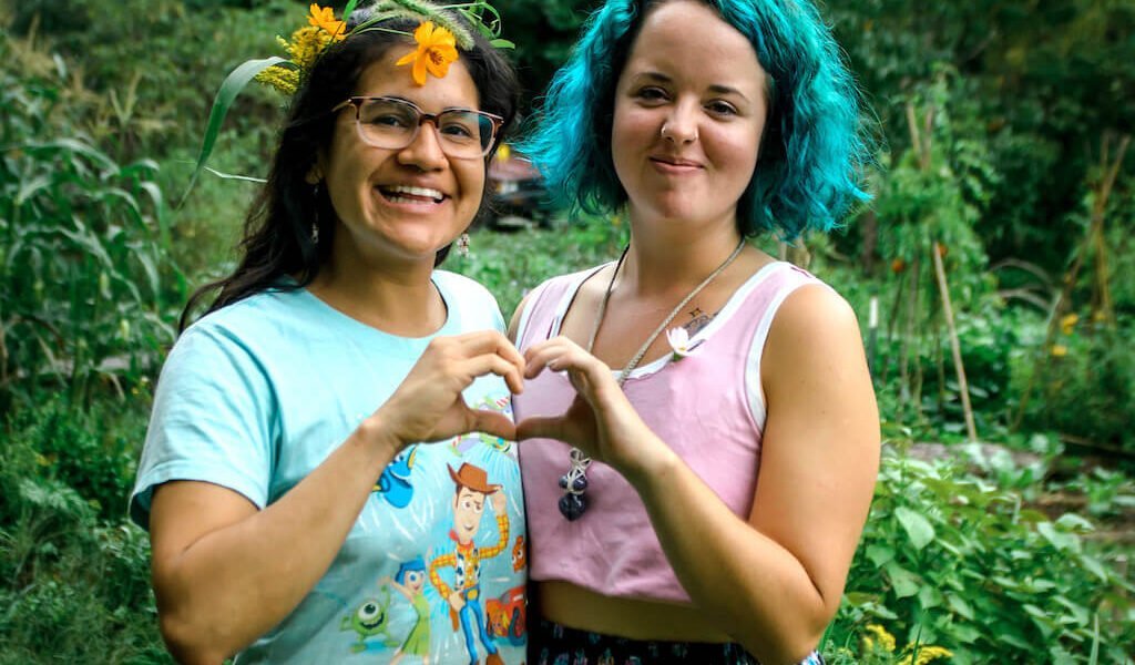 Two young women make a heart with their hands during women's rewilding weekend