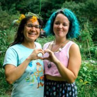 Two young women make a heart with their hands during women's rewilding weekend