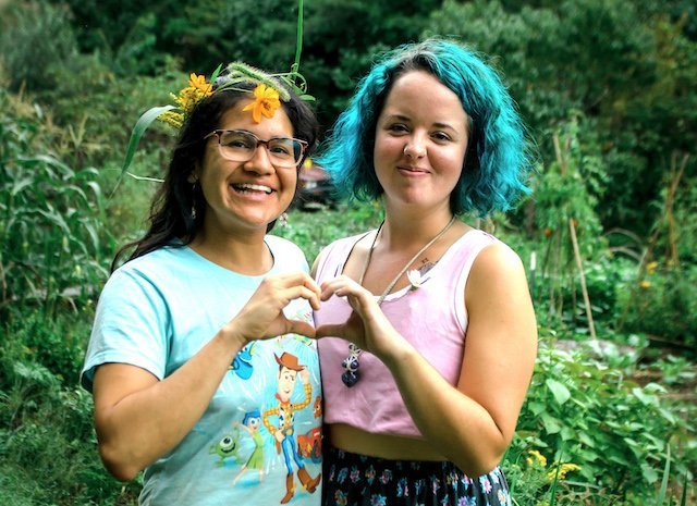 Two young women smiling and making a heart with their hands together during a Women's Rewilding class