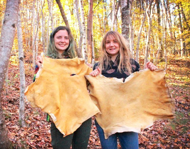 2 young women with finished hides during hide tanning class