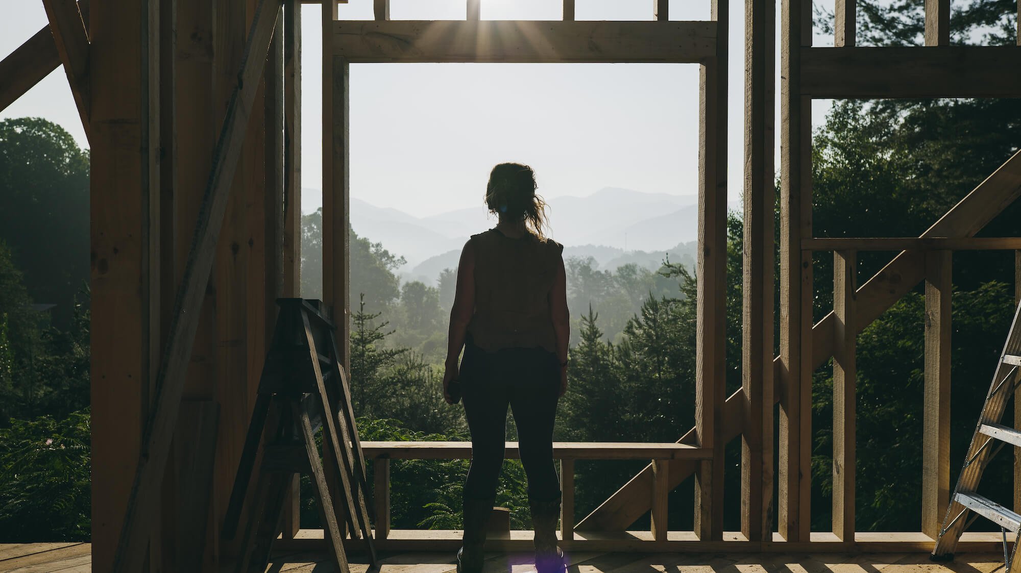 woman standing in front of rough window opening in tiny house