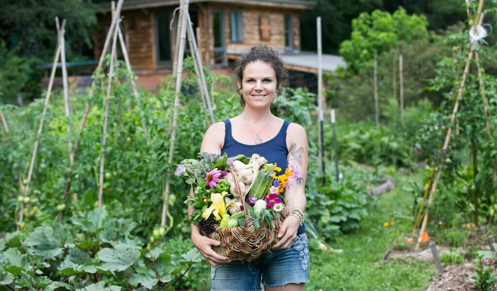 Woman with abundant basket in front of garden