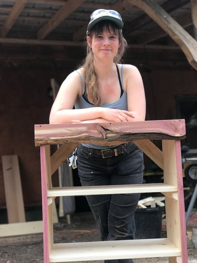 Woman poses with shelf she built during women's basic carpentry class