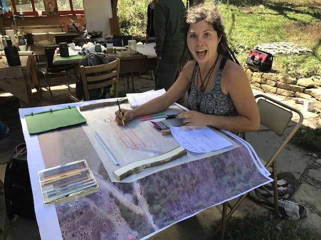 Student designs at table during permaculture design class