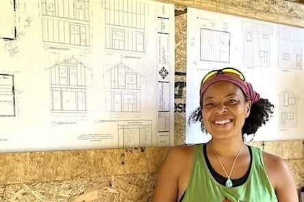 Woman poses in front of plans during tiny house workshop