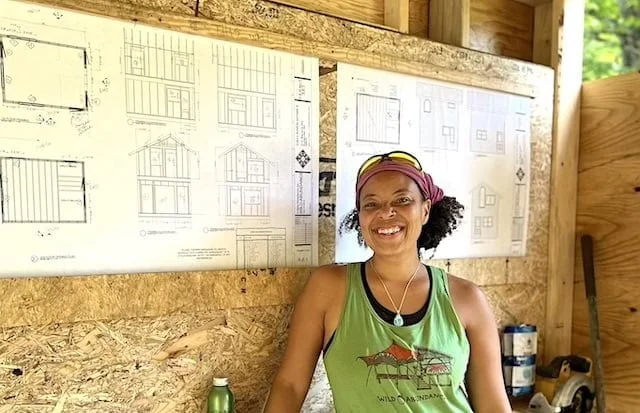 Woman poses in front of plans during tiny house workshop