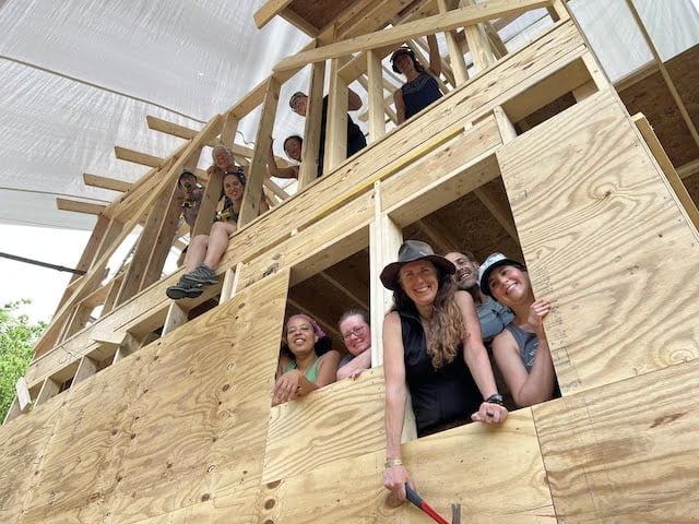 Students peek out of tiny house during tiny house workshop