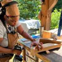 A women's carpentry student uses a drill to screw wood together