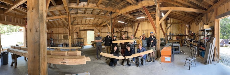 Students pose with timber inside timber framed barn during class