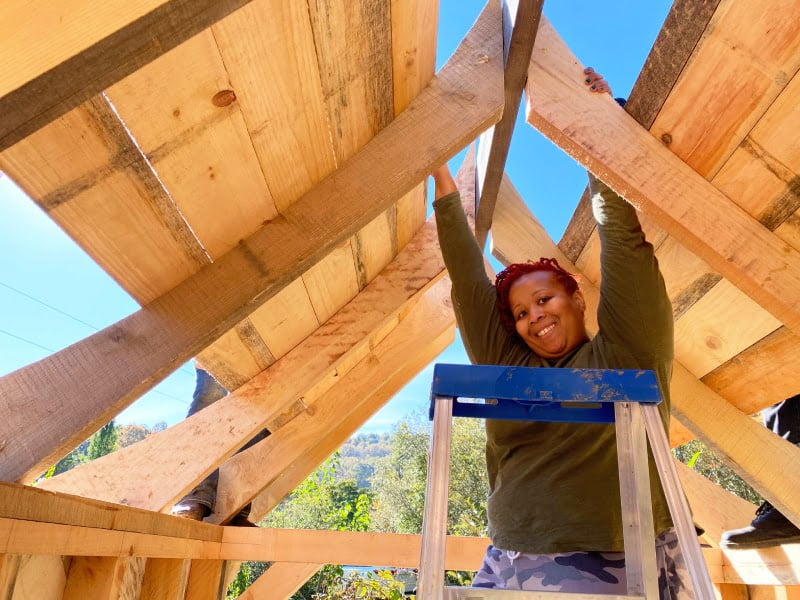student putting a roof on a tiny house