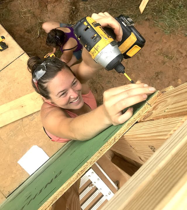 Woman uses drill to attach board during women's basic carpentry class